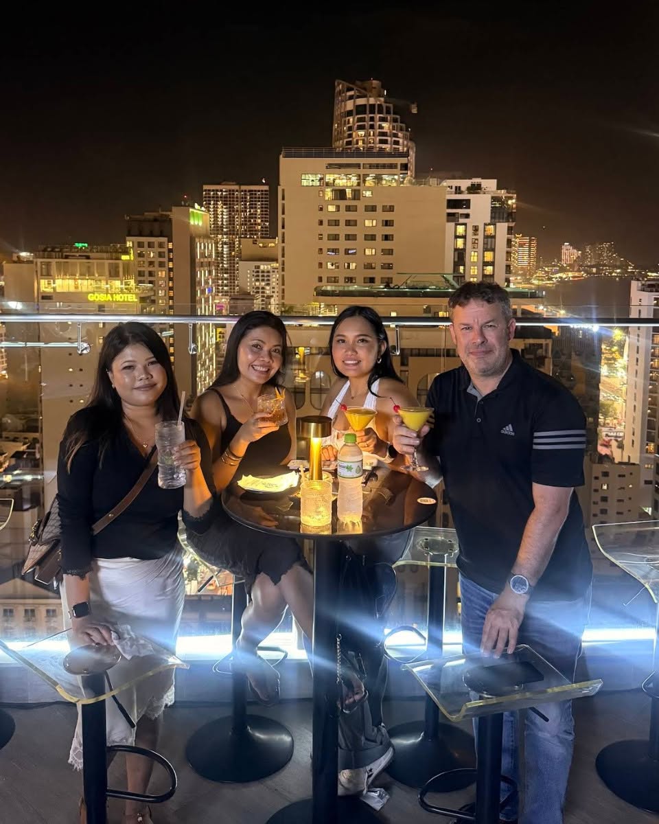 Friends enjoying drinks on the JD68 rooftop with the city behind them