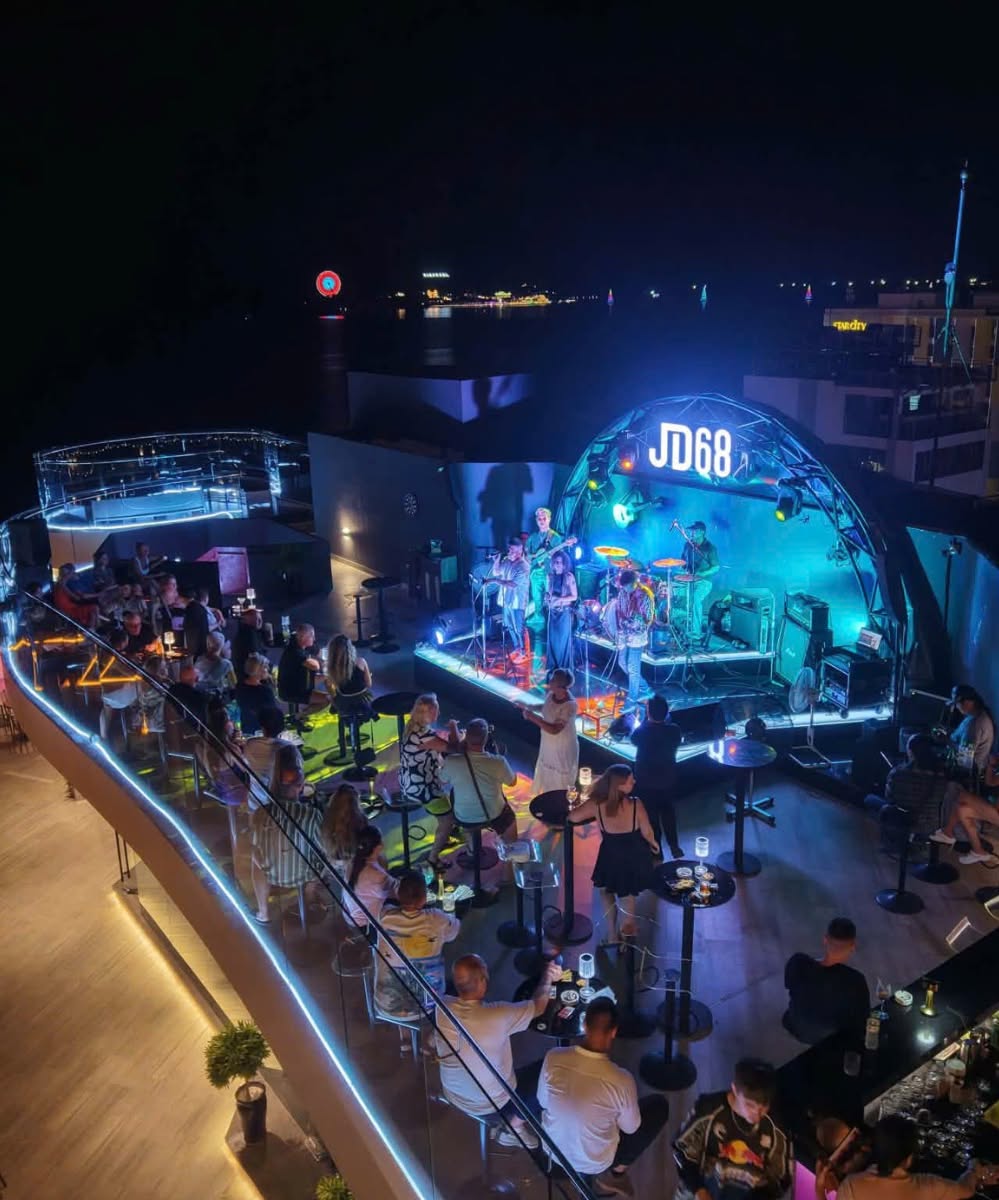 Live band performing on the JD68 rooftop stage above the city